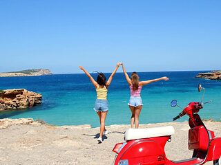 Two beautiful girls have fun on the beach with a guy, showcasing sensual moves.