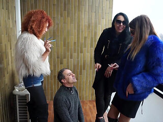 Fur-clad Femdoms Dominate Submissive on Balcony