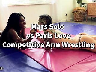 Topless women engage in energetic arm wrestling.