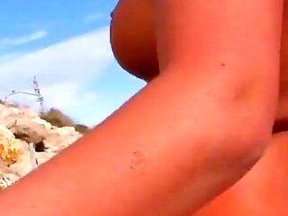 A slut with two soft breasts and blonde hair is ready for some ass fucking on the beach